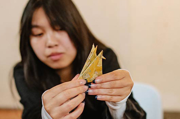 an adult folding a yellow paper into an origami shape